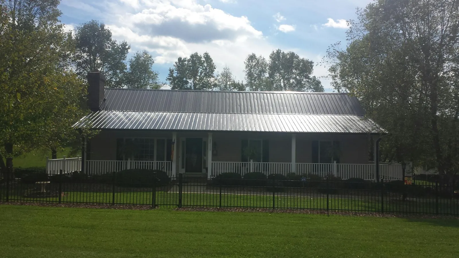 Gray metal roof on a brick ranch with a full width front porch — Gutter Guard Installation work by our crew in Payson