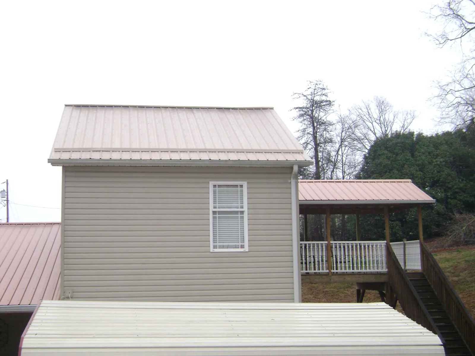 Tan metal roofs on a two story addition and attached porch, from a Roof Replacement job in Payson
